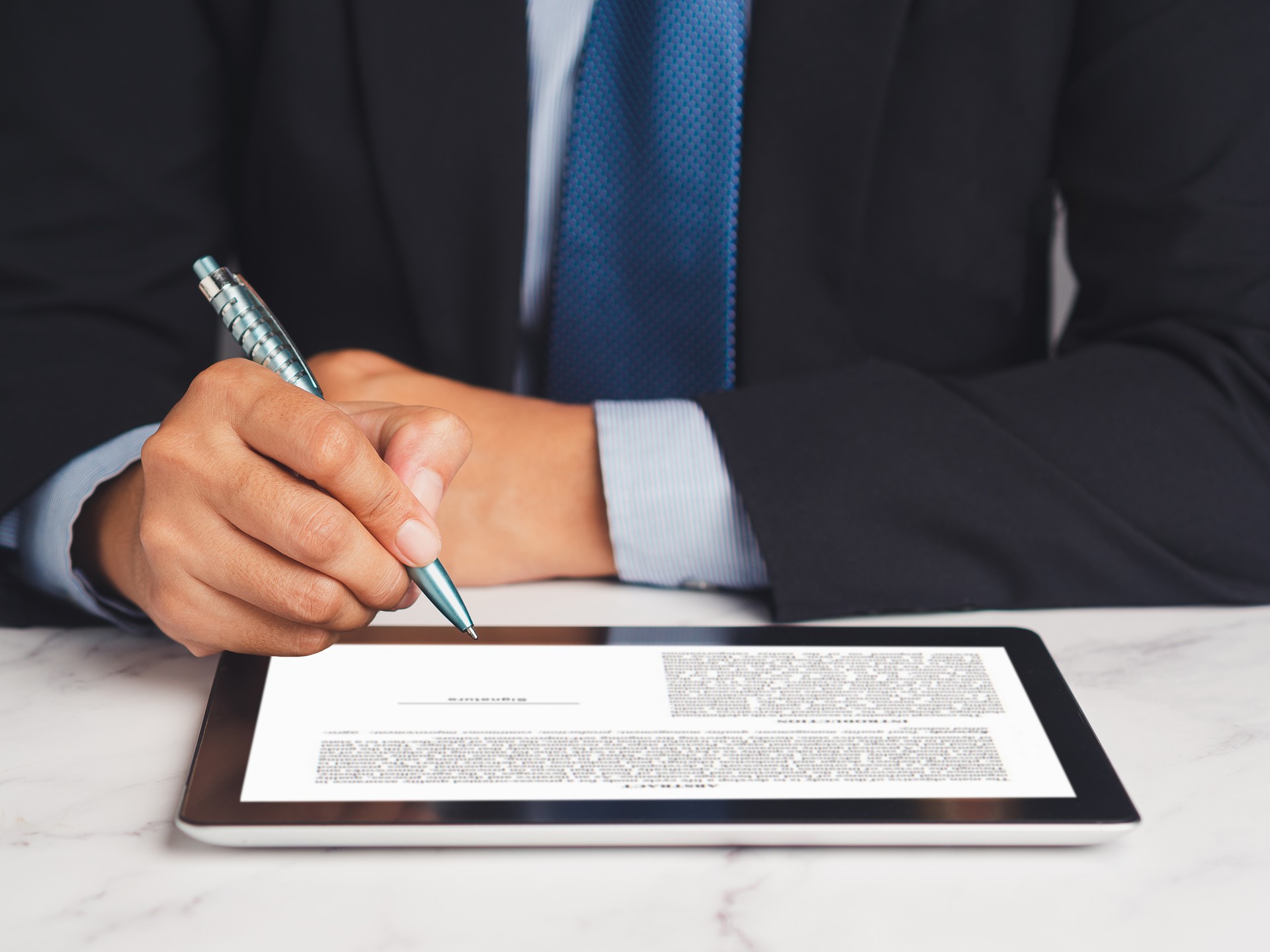 Signature electronic. Businessman signing a digital contract or agreement on a tablet while sitting in the office